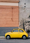 A yellow vintage car parked beside a textured wall on the Amalfi Coast Drive XII.