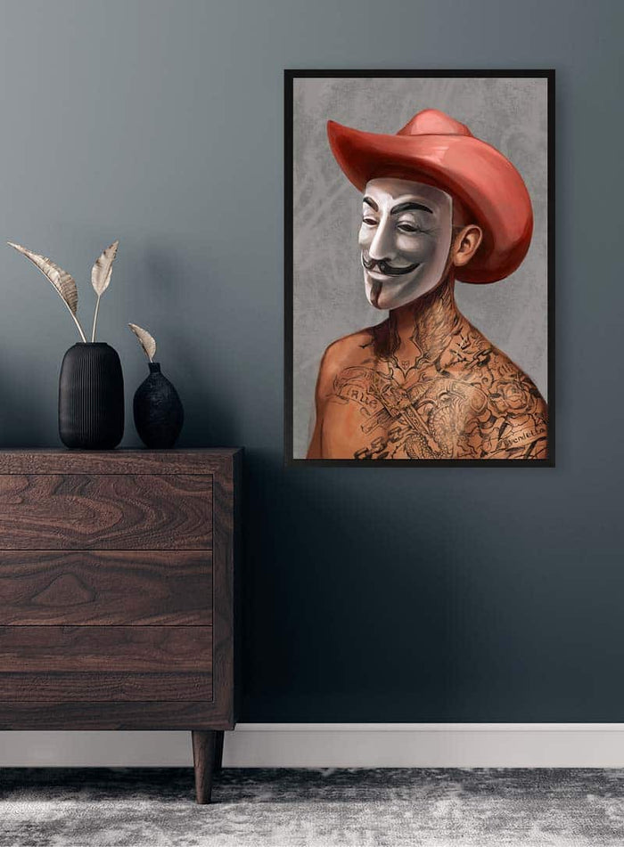 Framed art of a tattooed person wearing an Anonymous Guy Fawkes mask and red cowboy hat on a gray wall.