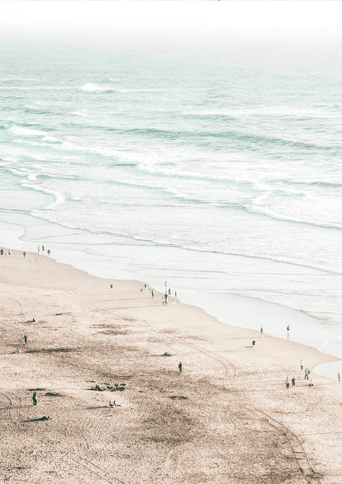 A serene beach scene with gentle waves and people walking along the sandy shore, perfect for coastal decor.