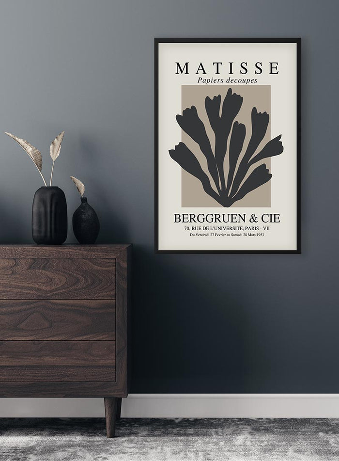 Black Papier Decoupe poster in a modern frame, displayed above a wooden dresser against a dark wall.