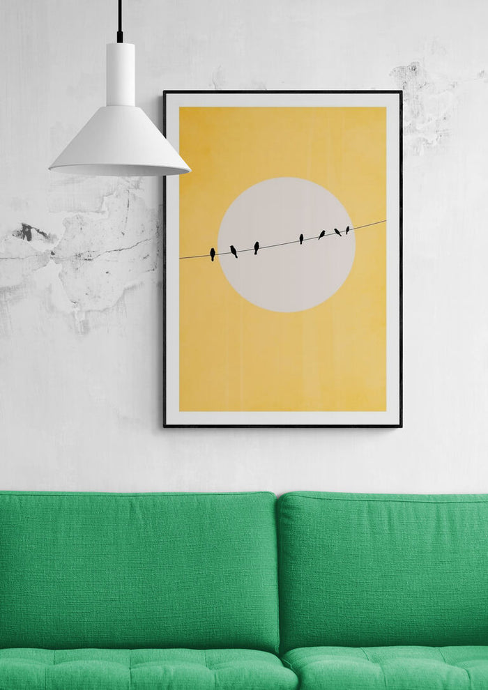 Framed Chirping and Chilling print by Boris Draschoff above a green sofa in a modern living room.