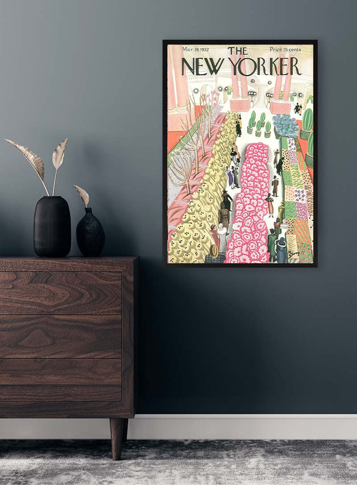 Framed Colorful Artfair Plakat hanging on a dark gray wall above a wooden dresser with vases and dried plants.