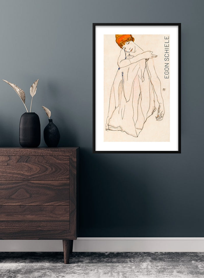 Framed Dancer (1913) by Egon Schiele poster displayed on a dark wall above a wooden dresser.