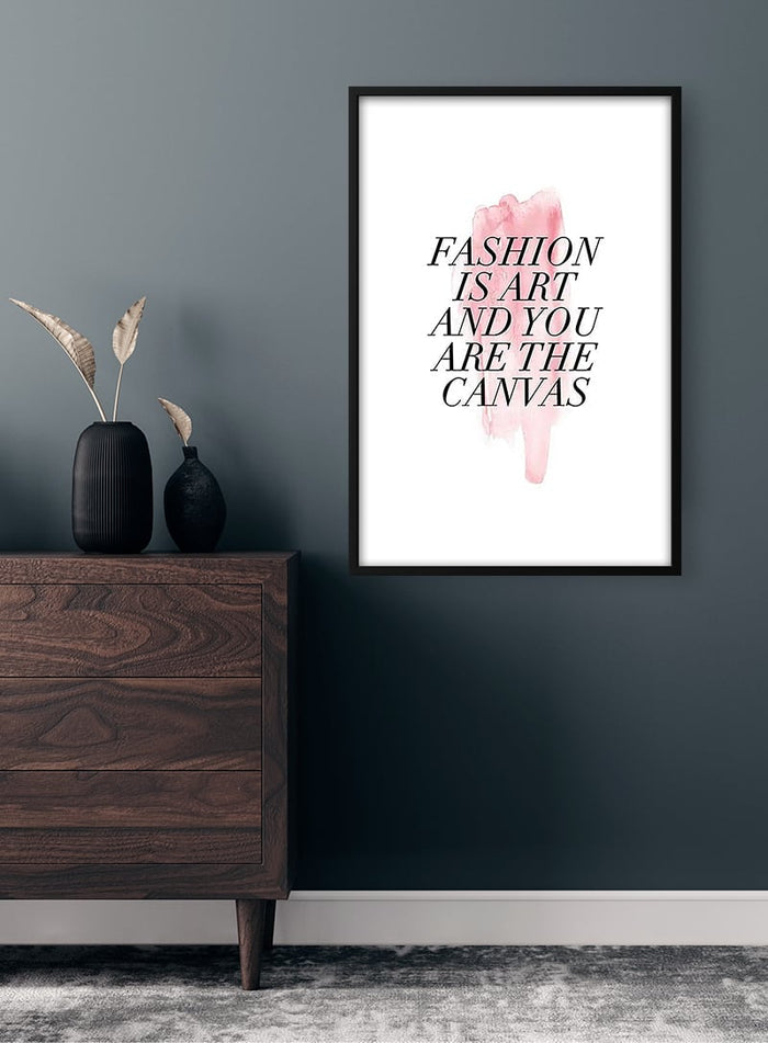 Framed "Fashion Is Art and You Are the Canvas" quote poster hanging on a modern grey wall above a dresser.