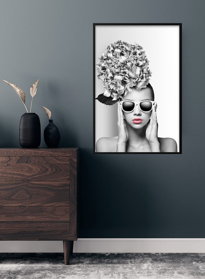 Poster of a woman wearing sunglasses and large floral headpiece, styled in black and white with pink lips.