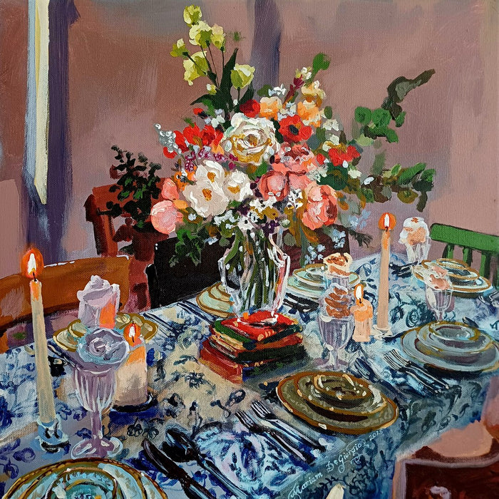 Friday banquet no. II by Mariam De Giorgio — a candlelit table laid with a blue-and-white cloth and a large bouquet of roses and peonies.