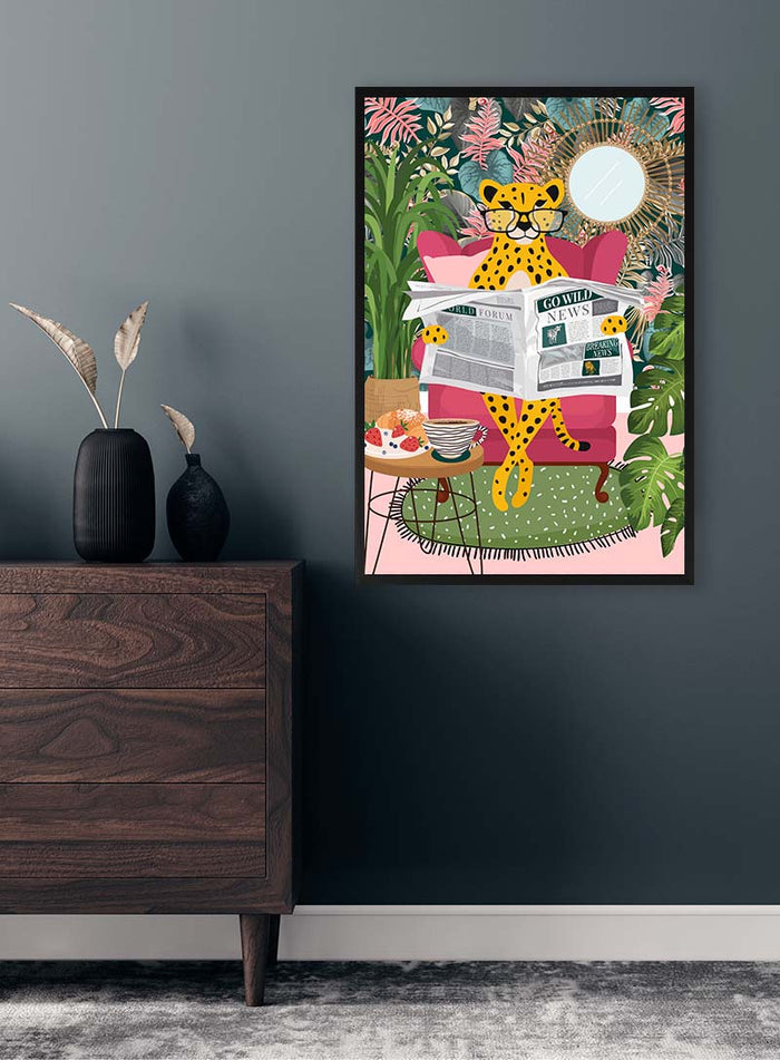 Framed artwork of a leopard reading newspapers on a pink chair, surrounded by plants, displayed above a dresser.