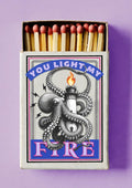 Light My Fire by Daniel Leo — vintage matchbox poster with an engraved octopus wrapped around a flaming lighthouse