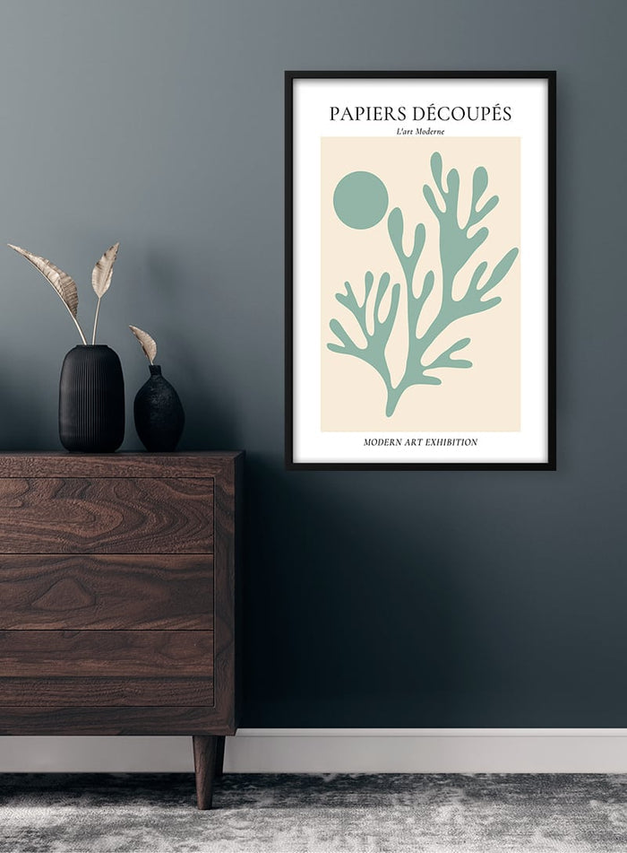Minimalist poster of green coral and sun, inspired by Matisse, hanging above a wooden dresser on a dark wall.