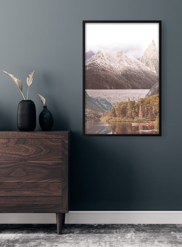 Framed Mountain lake and trees Plakat displayed on a dark wall above a wooden dresser with decorative vase.