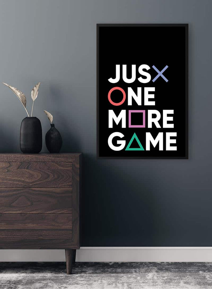 Framed "Just One More Game" poster with gaming symbols, displayed above a dresser in a modern room.