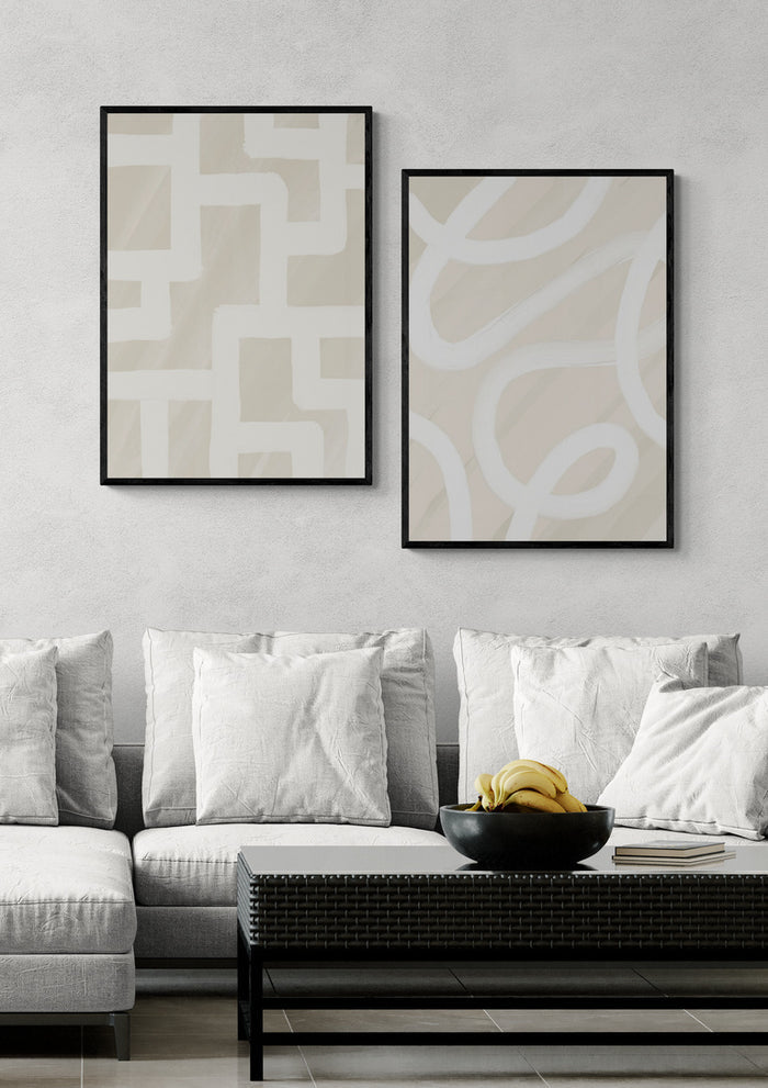 Two Quiet Structure - Yuli abstract prints in black frames hang above a modern sofa with light cushions.