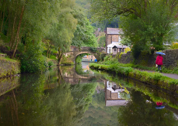 Red Coat on the Towpath by Northern Gnome Photography - a woman in red beside a still canal with a stone bridge