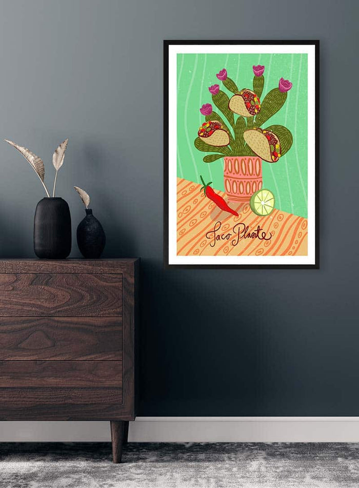 Colorful framed Taco Plante - Nina Broen print on wall above wooden dresser with vases and dried grasses.