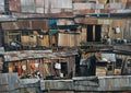 The others by Adrian DeDea - detailed painting of a dense shanty town of rusty metal shacks