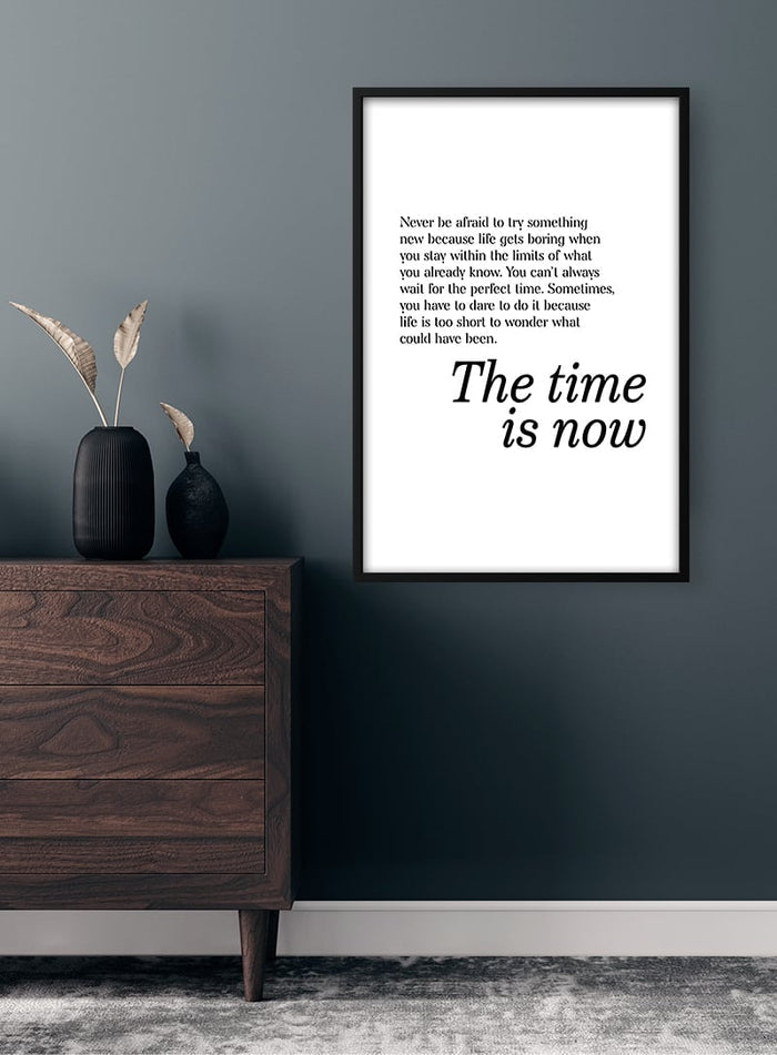 Minimalist "The Time Is Now" poster on wall above mid-century dresser with black vase and dried grasses.