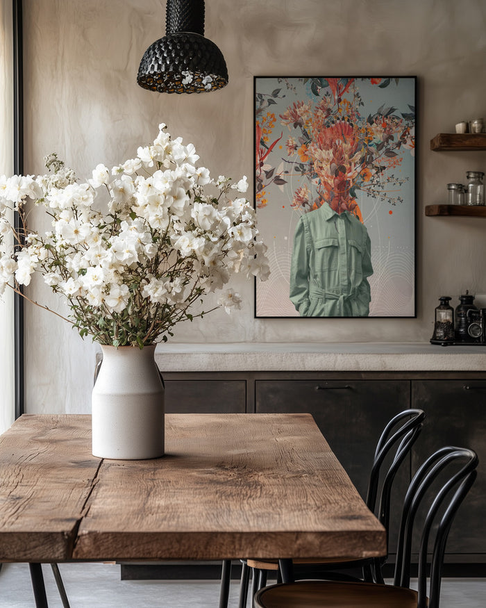 Framed "You Smell Like Home - Frank Moth" art on wall above rustic table with white flowers in vase.